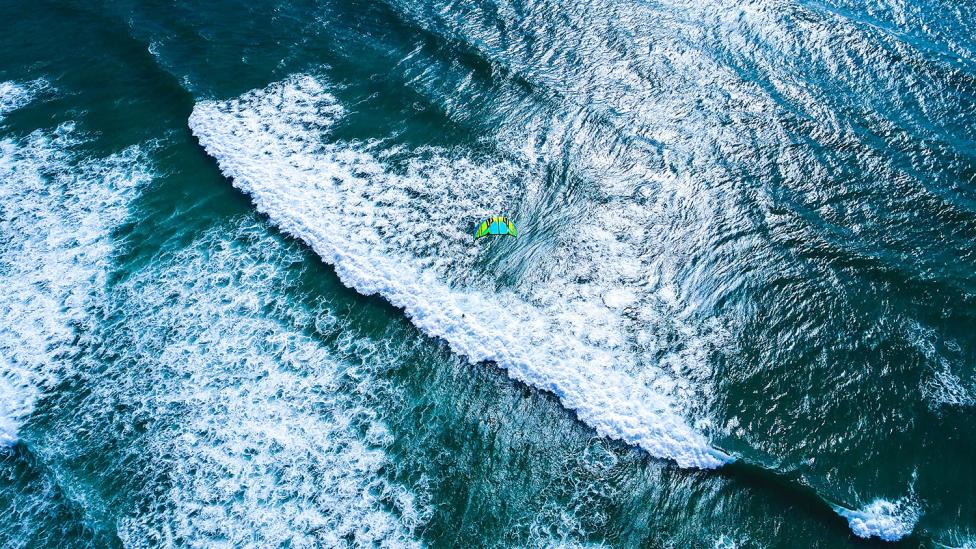 Kitesurfer omringd door duizenden haaien