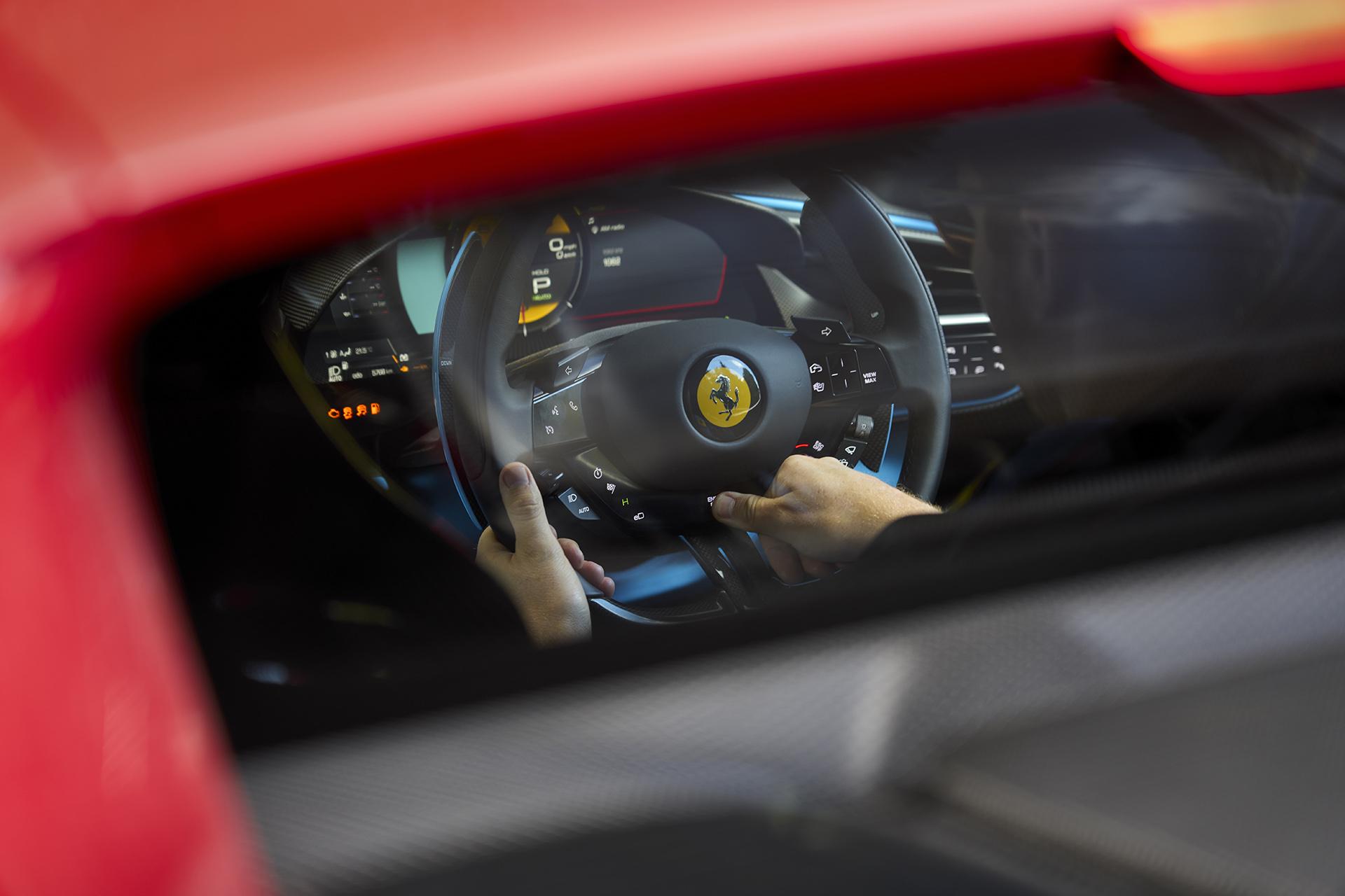 Ferrari 296 GTB stuur terwijl bestuurder op start-knop drukt