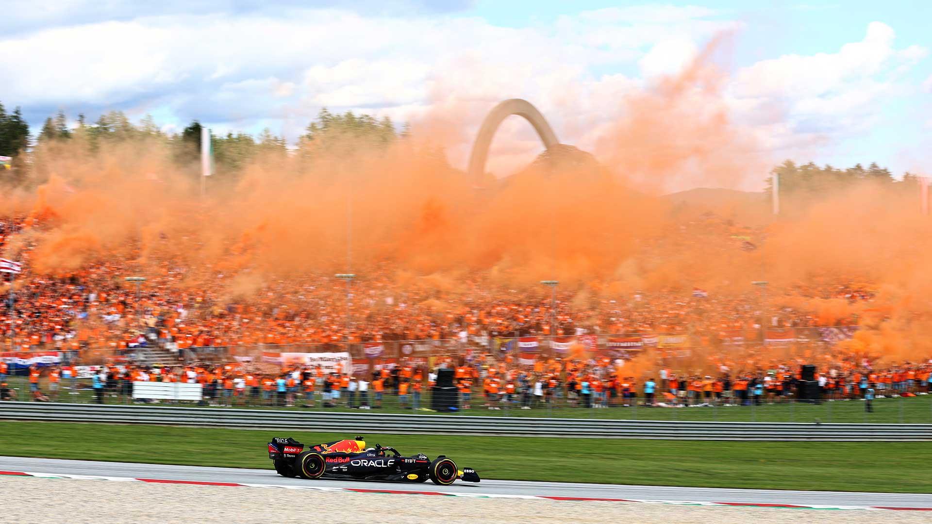 GP van Oostenrijk 2022 Sprint race Verstappen rijdend voor de oranjetribune met oranje rook