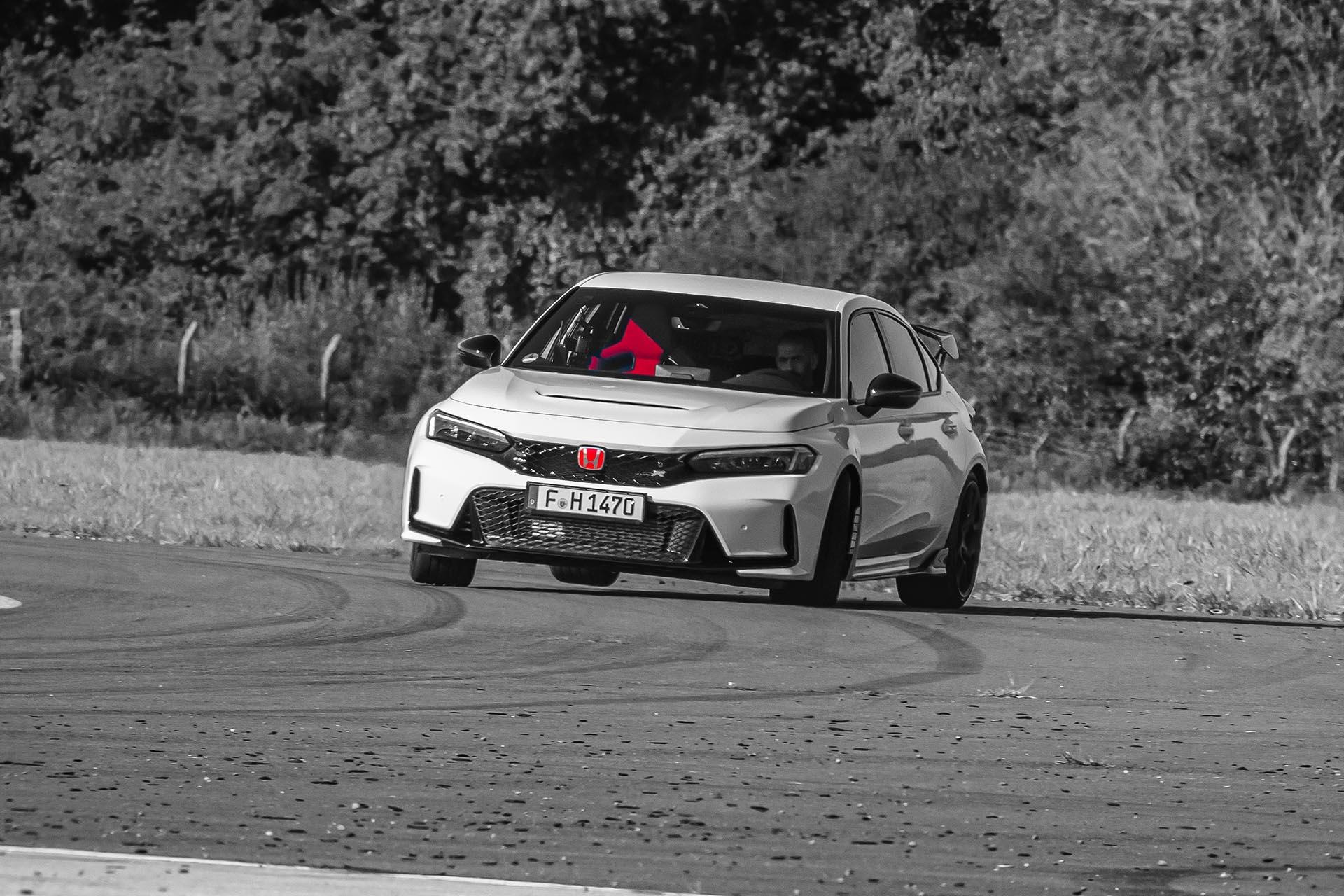 Honda Civic Type R rijdend op een weg schuin voor Chris Harris achter het stuur zwart wit
