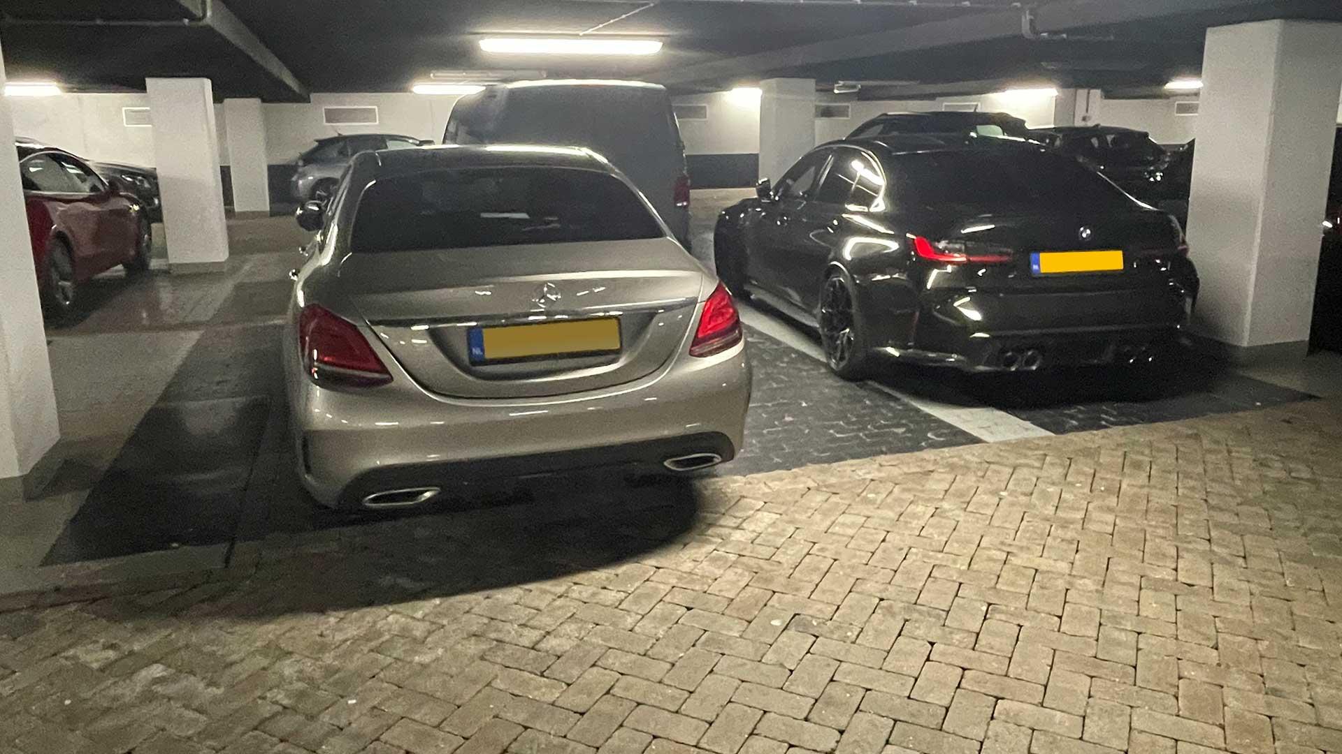Mercedes C-klasse parkeert op twee vakken naast BMW M3
