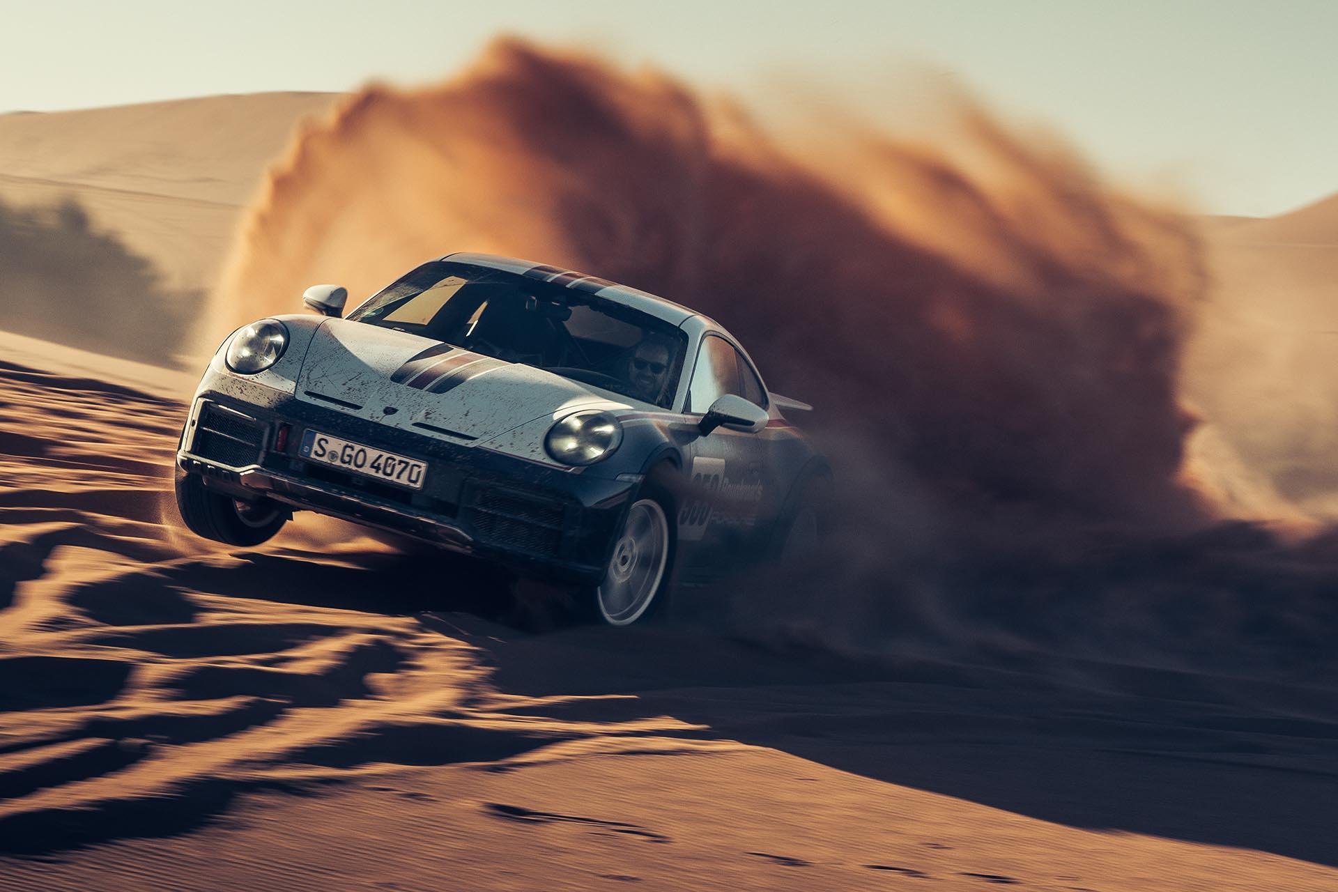 Porsche 911 Dakar rijdend in de woestijn schuin voor