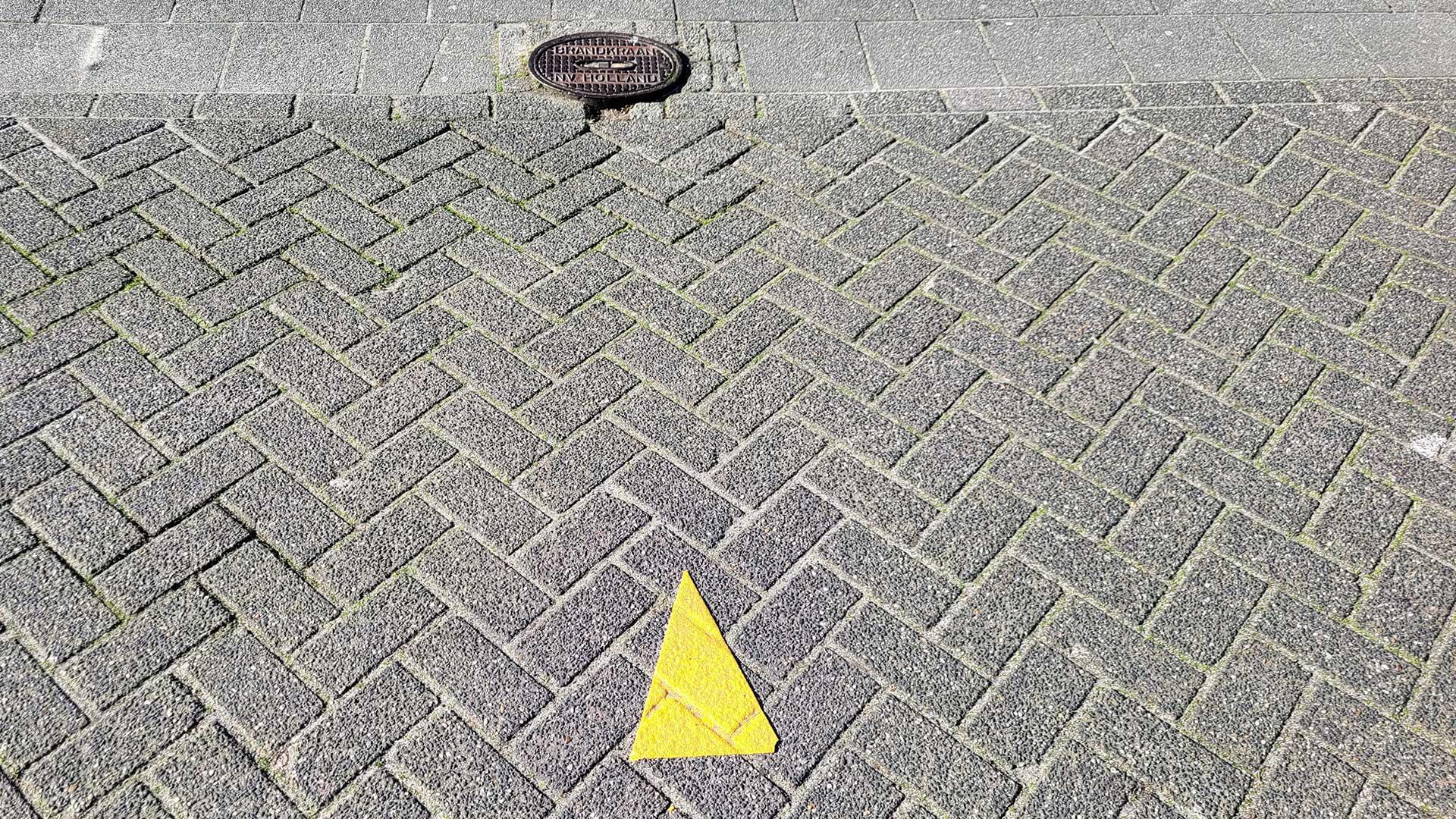 Gele driehoek op het wegdek wijst naar wateraansluiting