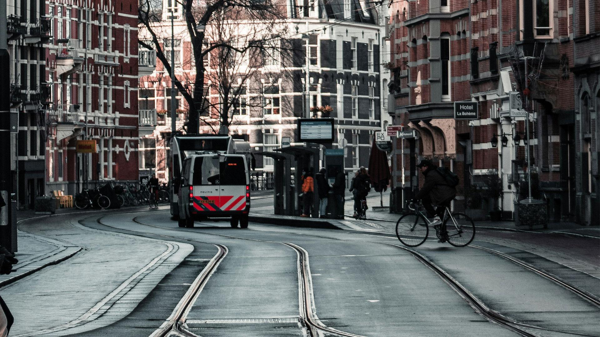 straat in Amsterdam met tramrails en een politiebus