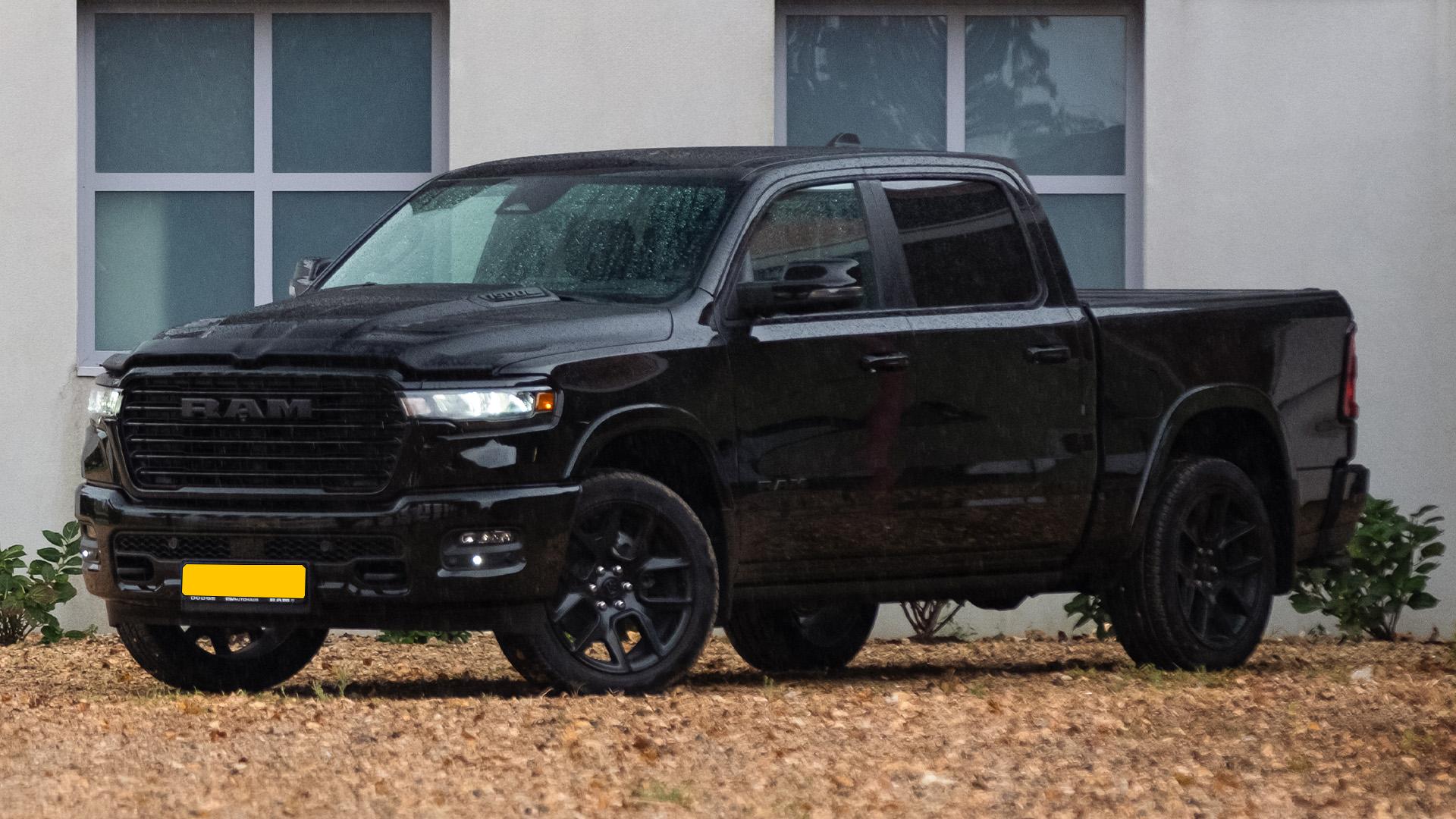 RAM 1500 zwart (2025) zijkant voor schuin links in het zand