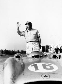 Juan Manuel Fangio staand in auto