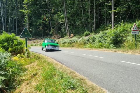 Renault 5 elektrisch rijdend op een weg overhellend