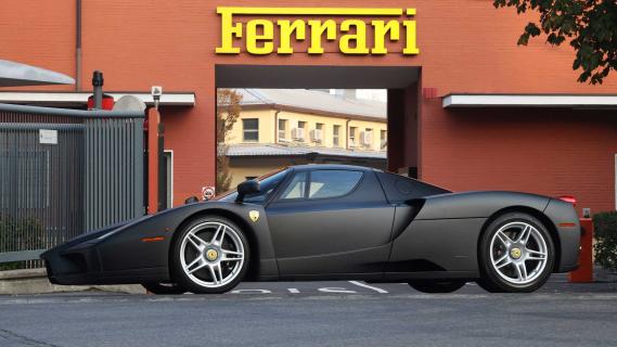 Ferrari Enzo matzwart zijkant voor de Ferrari-fabriek in Maranello