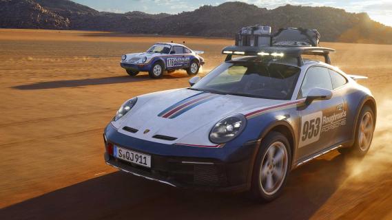 Porsche 911 Dakar Roughroads kleurstelling en oude Porsche 953 met Rothmans kleurstelling rijdend op een zandweg schuin voor