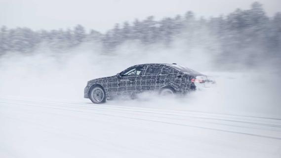 BMW i5 testauto driftend op een bevroren meer schuin achter