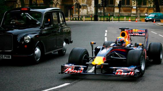 Red Bull F1-auto rijdend naast een Londense zwarte taxi