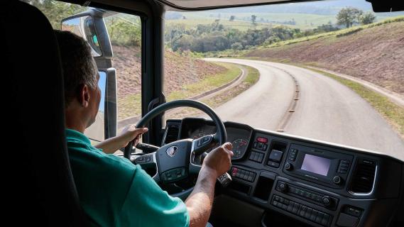 Scania vrachtwagen aan het rijden met een chauffeur achter stuur