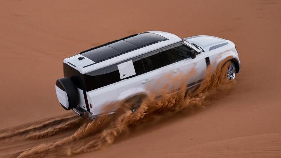 Defender 130 X-Dynamic HSE P400 MHEV (Land Rover) 3/4 achter rijdend zand woestijn offroad