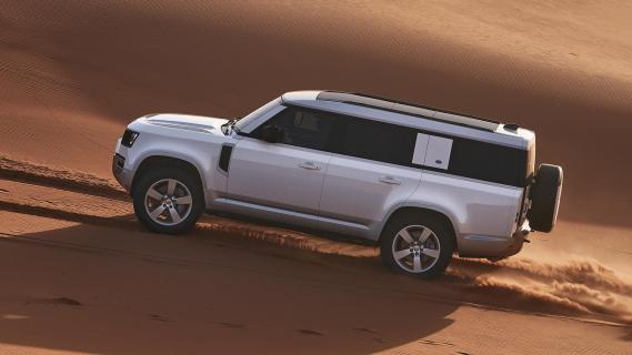 Defender 130 X-Dynamic HSE P400 MHEV (Land Rover) zijkant rijdend zand woestijn offroad