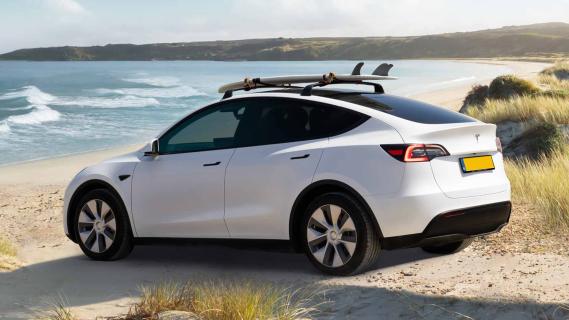 Tesla Model Y wit schuin achter strand surfplank Nederlands kenteken