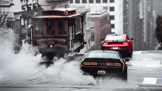 Dodge Challenger en Ford Mustang rijdend achterkant in stad rook