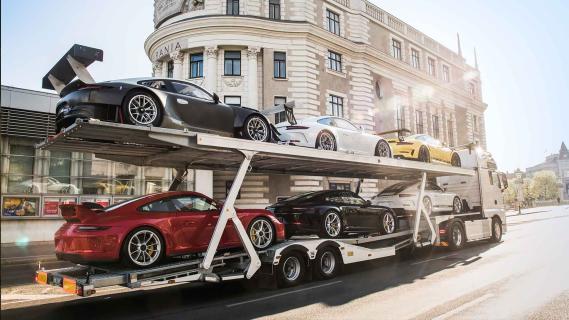 Porsche 911-collectie te koop met vrachtwagen en trailer vrachtwagen rijdend schuin achter