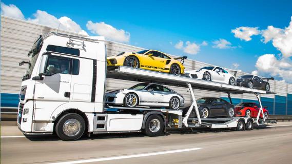 Porsche 911-collectie te koop met vrachtwagen en trailer vrachtwagen rijdend schuin voor snelweg