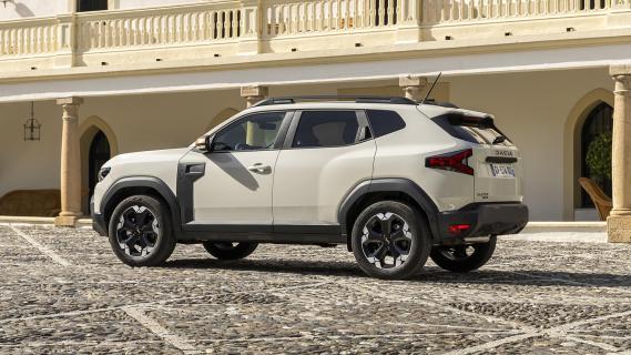 Dacia Duster Hybrid 140 Extreme grijs (2025) zijkant links schuin achter op binnenplein