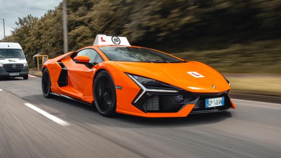 Lamborghini Revuelto lesauto oranje zijkant rechts schuin voor rijdend