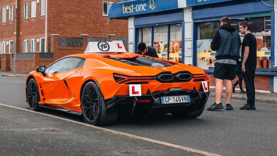 Lamborghini Revuelto lesauto oranje zijkant links achter schuin op straat stilstaand