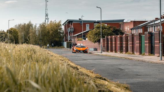 Lamborghini Revuelto lesauto oranje voorkant veraf in afgelegen straat