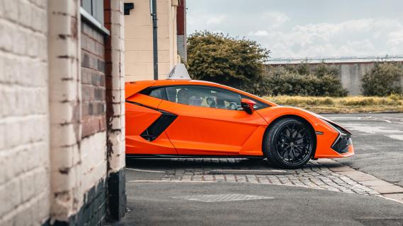 Lamborghini Revuelto lesauto oranje zijkant rechts uitrit straat