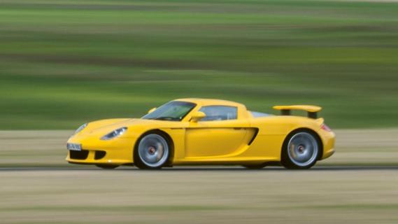 Porsche Carrera GT (980) geel zijkant voor rijdend grasveld