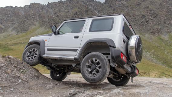 Suzuki Jimny Mata (2024) grijs zijkant links achter rotsen