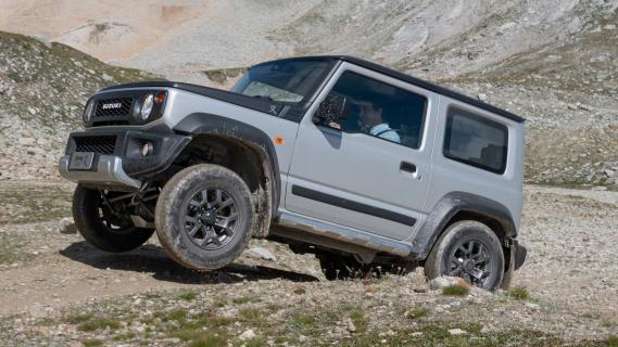 Suzuki Jimny Mata (2024) grijs zijkant linksvoor schuin heuvel voorwielen los van grond