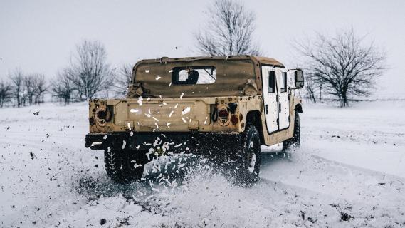 AM General Humvee rijdend door sneeuw zijkant achter schuin