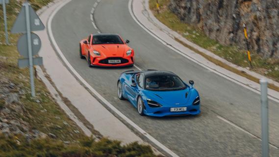 Aston Martin V8 Vantage oranje McLaren 750S blauw zijkant voor schuin boven hoog rijdend op weg