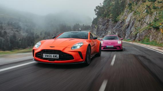 Aston Martin V8 Vantage oranje Porsche 911 S/T roze voorkant zij bergweg bergwand rijdend