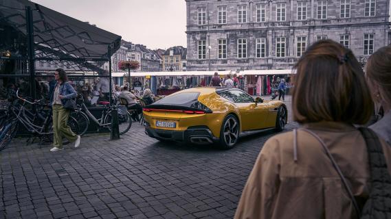 Ferrari 12Cilinderi geel zijkant rechts achter schuin dorp mensen