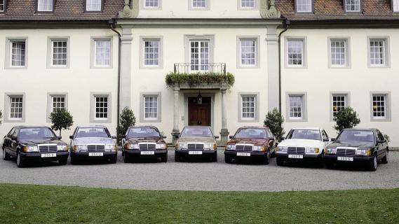 Mercedes W124 modellen op een rij vooMercedes 300e met mensen met een vlag vraag ons niet waaromr een groot huis