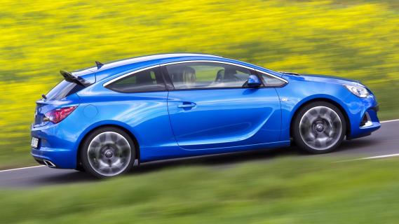 Opel Astra OPC (2012) blauw zijkant schuin rechts rijdend gras