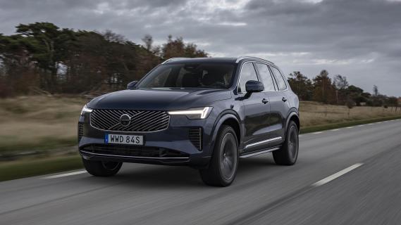 Volvo XC90 T8 blauw (2025) zijkant links voor rijdend grijze lucht maar dan iets dichterbij