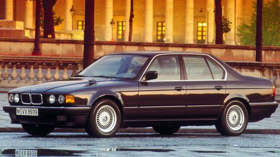 BMW 750i (E32) zwart (1987) voorkant lijks zijkant natte ondergrond