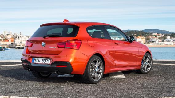 BMW M135i (F21) oranje (2015) zijkant achter rechts schuin