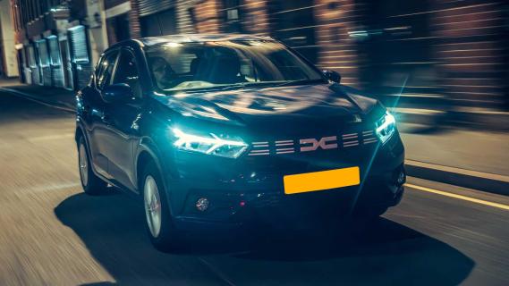 Dacia Sandero in het donker met koplampen aan