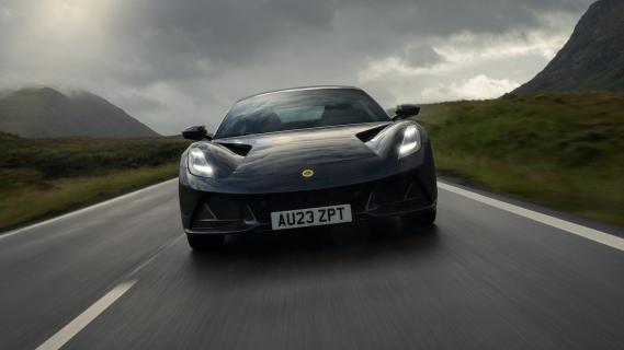 Lotus Emira i4 grijs (2025) voorkant rijdend op weg donkere lucht wolken