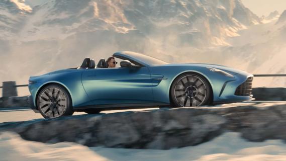 Aston Martin Vantage Roadster groen (2025) zijkant rechts rijdend door bergen sneeuw