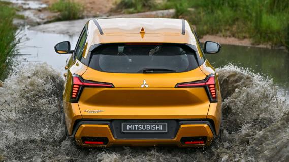 Mitsubishi Outlander Sport oranje (2025) achterzijde rijdend door modder plas