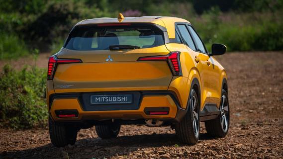 Mitsubishi Outlander Sport oranje (2025) zijkant rechts schuin achter rijdend op zandpad