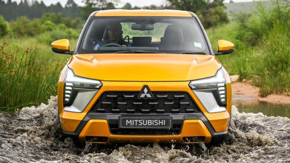 Mitsubishi Outlander Sport oranje (2025) voorzijde rijdend door modder plas