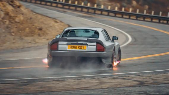 TWR Supercar Jaguar XJS restomod grijs (2025) achterkant driften vuur uit uitlaat op bergweg in bocht