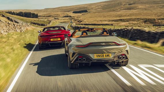 Aston Martin Vantage Roadster grijs & Ferrari Roma Spider rood zijkant achter rijdend