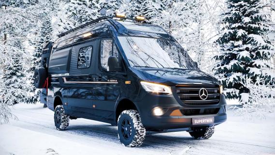 Adria Supertwin 4x4 (2024) zwart zijkant rechts schuin in de sneeuw lampen aan