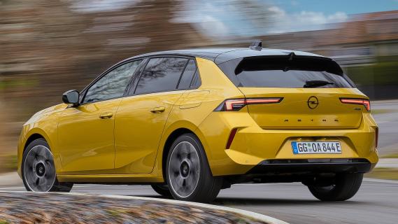 Opel Astra Hybrid geel (2025) zijkant links schuin achter rijdend door bocht