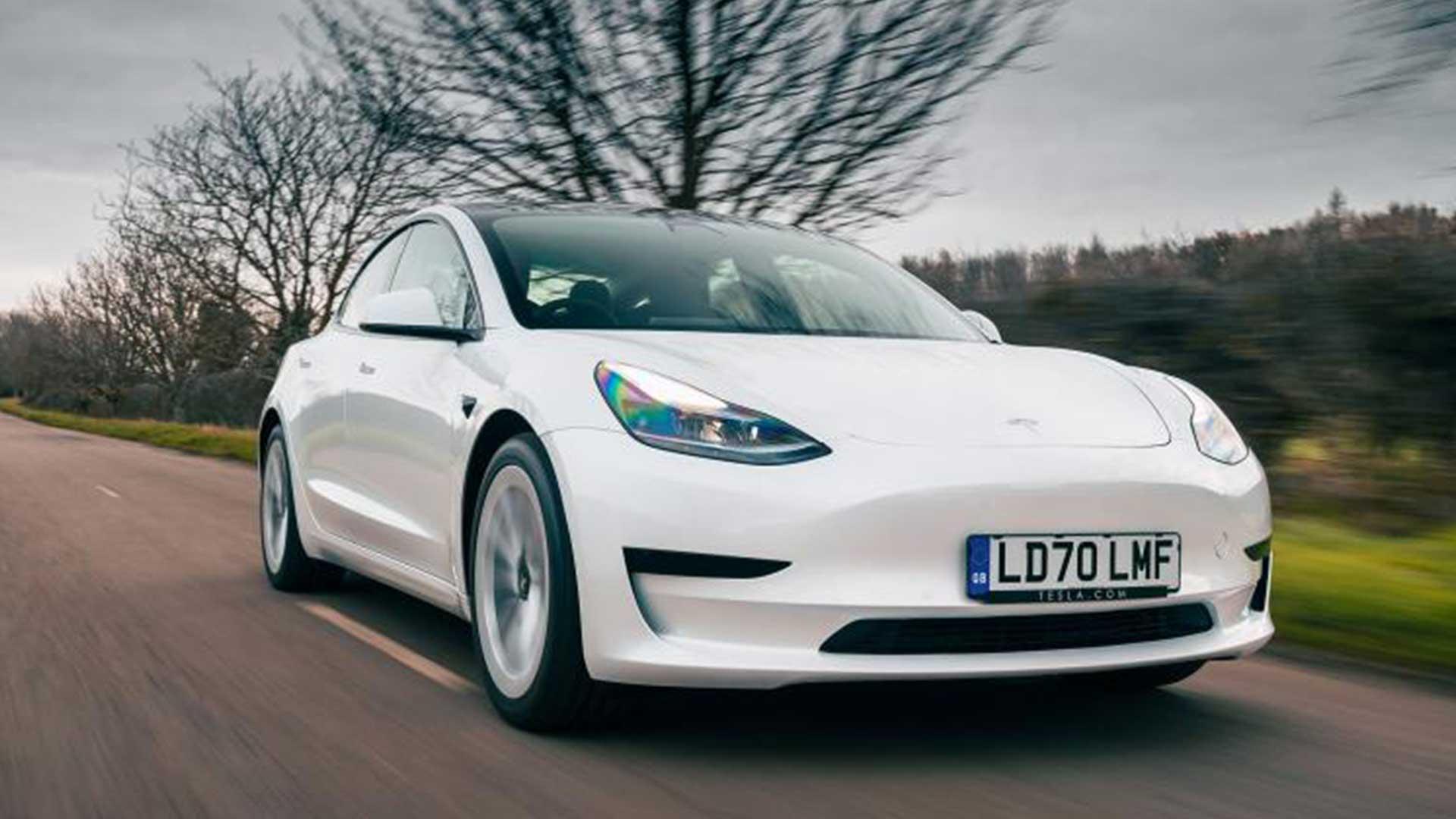 Tesla Model 3 rijdend op een weg schuin voor